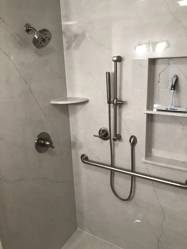 Marble-look shower panels with grab bars, handheld shower on a slide bar and recessed niche