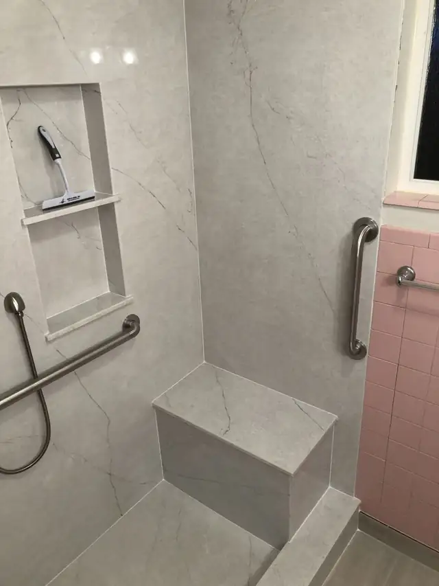 Walk-in shower with marble-look wall panels, built-in seat, recessed niche, grab bars and handheld shower